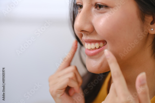 Tableau sur toile A woman is smiling and pointing at her teeth