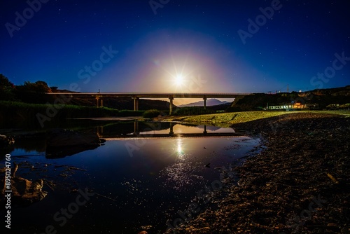 The moon iluminates a bridge over the river