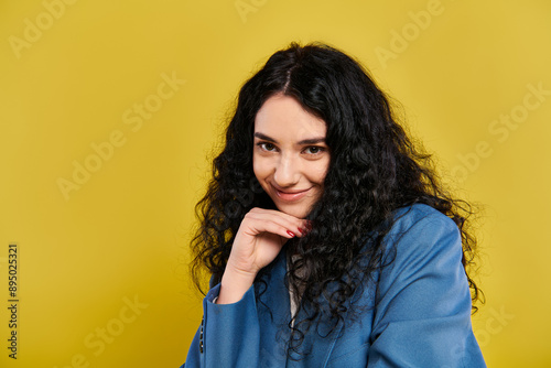 A young woman with long black hair and a blue shirt, exuding confidence and style against a vibrant yellow background. © LIGHTFIELD STUDIOS