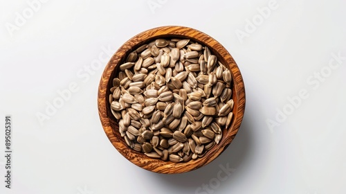 Roasted unpeeled sunflower seeds in wooden bowl on white background top view