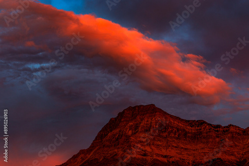 Dramatic glowing red cloud at sunset over a glowing mountain peak in Waterton Lakes National Park; Waterton, Alberta, Canada