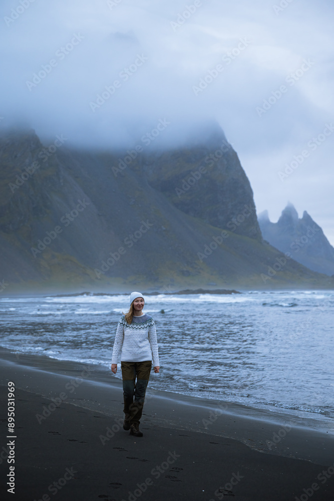 young woman walks on a black beach in Iceland young woman walks on a black beach in Iceland