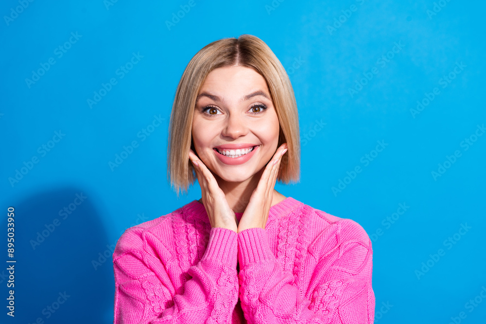 Portrait of nice young woman arms touch cheeks wear pink sweater isolated on blue color background Portrait of nice young woman arms touch cheeks wear pink sweater isolated on blue color background