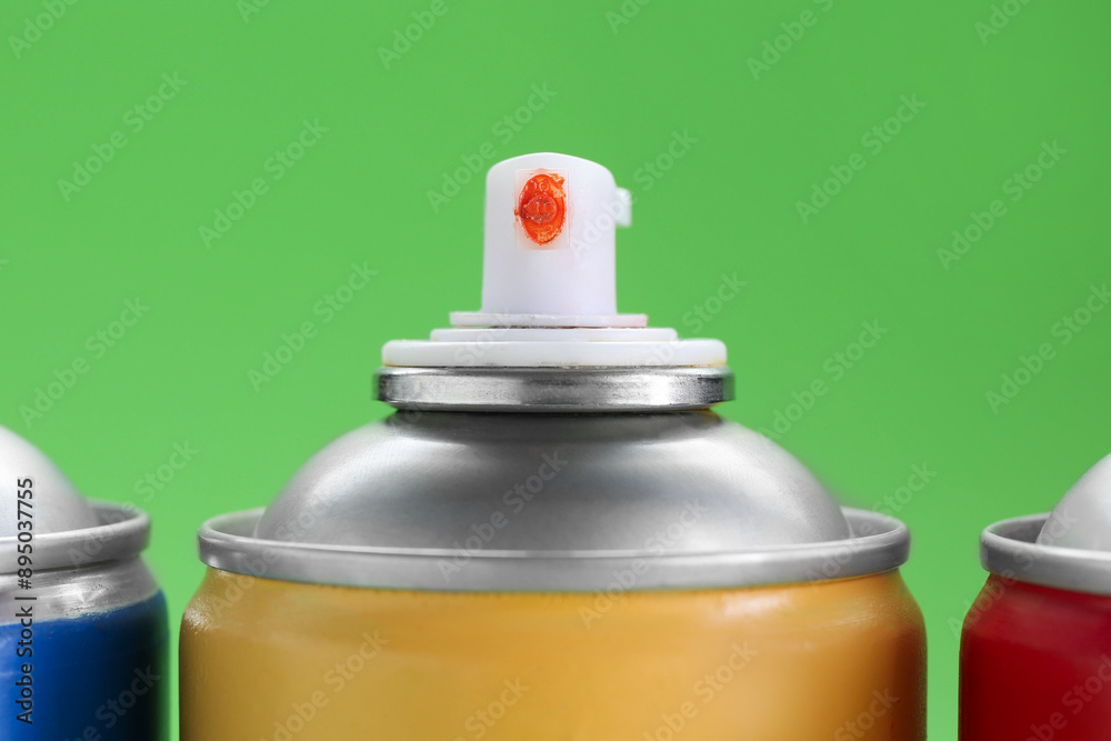 Many spray paint cans on green background, closeup Many spray paint cans on green background, closeup
