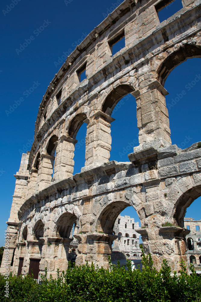 View through the stone structure of the ancient Roman Amphitheater, the Pula Arena with a blue sky, constructed in 27 BC - AD 68; Pula, Croatia View through the stone structure of the ancient Roman Amphitheater, the Pula Arena with a blue sky, constructed in 27 BC - AD 68; Pula, Croatia