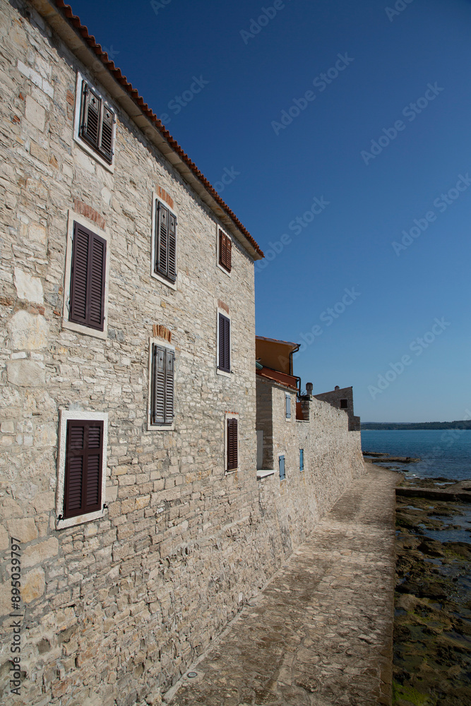 Outer city wall with residences along the seaside in the old town of Novigrad, Croatia; Novigrad, Istria County, Croatia Outer city wall with residences along the seaside in the old town of Novigrad, Croatia; Novigrad, Istria County, Croatia