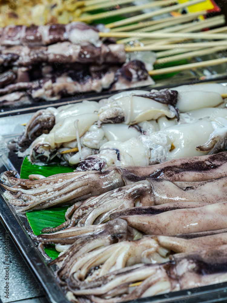 Squid and cuttlefish displayed on skewers at a market stall. Squid and cuttlefish displayed on skewers at a market stall.