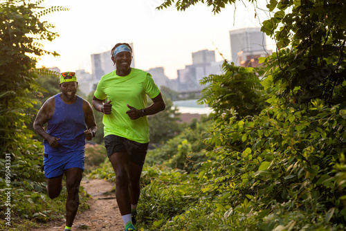 Two friends running trails with city skyline in background. photo