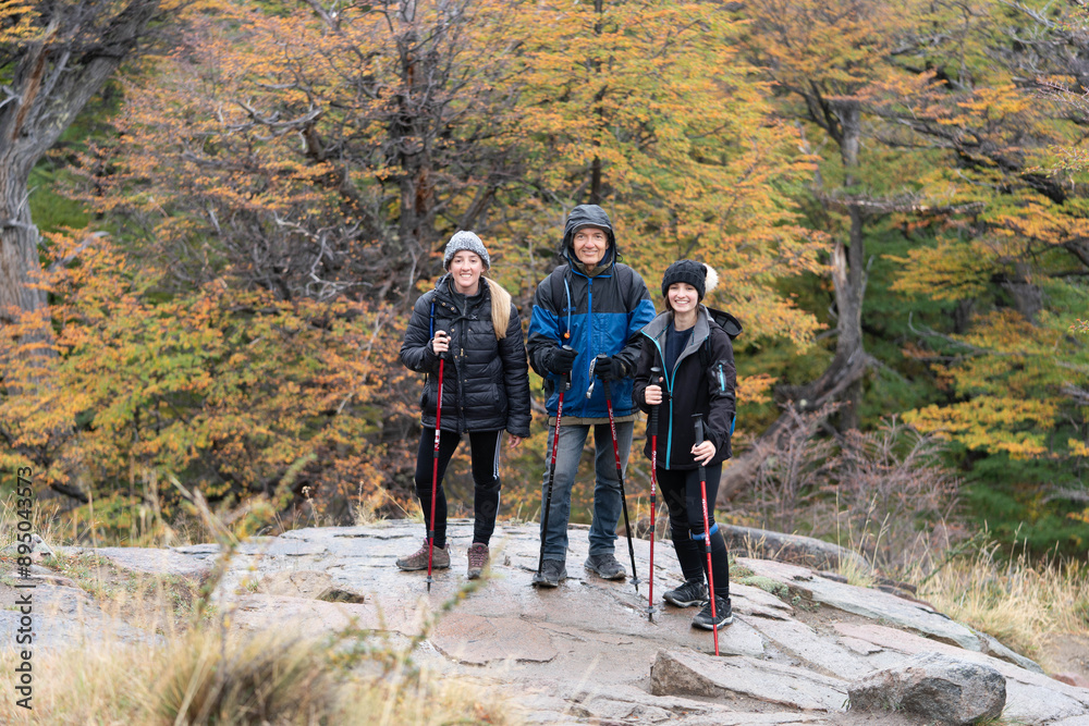 Three people are standing on a rocky hillside, wearing backpacks Three people are standing on a rocky hillside, wearing backpacks