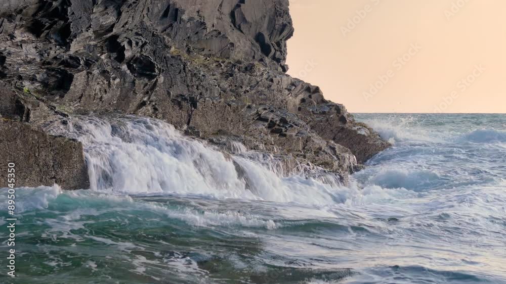 Waves crash into rugged sea cliffs along Cornish North Coast, UK. Low aerial Waves crash into rugged sea cliffs along Cornish North Coast, UK. Low aerial