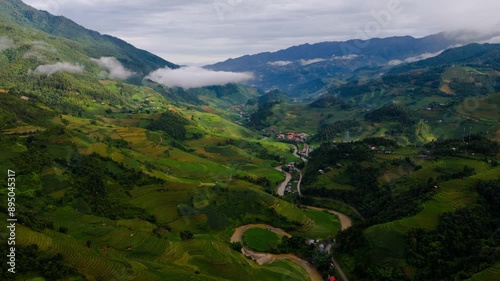 Terraced valley lit by moving morning light and rising mystic clouds forming as the sun rises.  Valley in Mu Cang Chai, Vietnam. photo