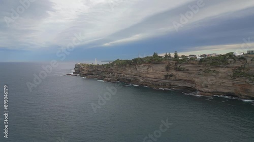 60 seconds aerial scenic flight of North Bondi, Sydney Australia featuring Aboriginal Rock Engravings and the famous white monument tower and beach side residential shots on a cloudy day photo