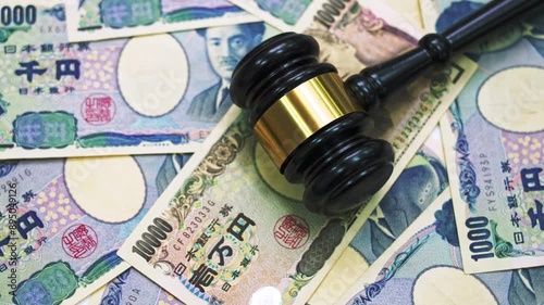 Gavel on stack of Japanese yen spinning on table