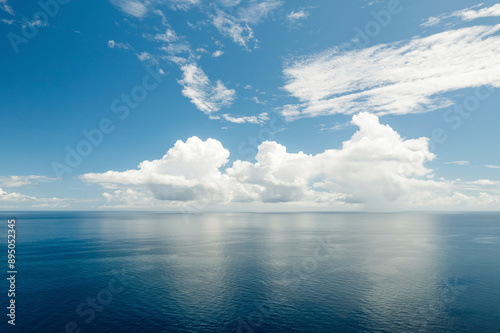 Bright clouds in a blue sky reflecting a mirror image into the tranquil blue water of the Molucca Sea at Kepulauan Togean National Park; Wakai, Central Sulawesi, Indonesia