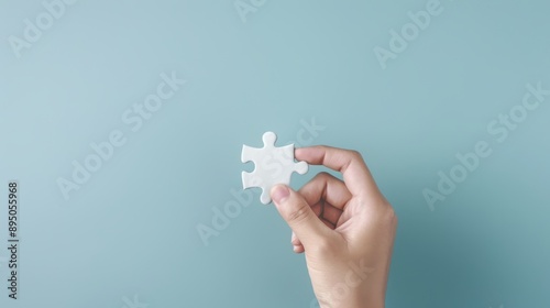 A hand holding a white puzzle piece