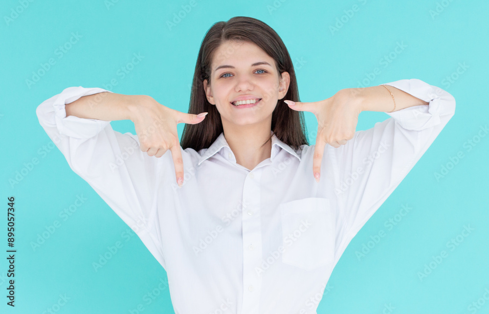 Smiling confident girl pointing fingers down to show advertisement, showing promo offer on bottom empty space, standing against blue background. Smiling confident girl pointing fingers down to show advertisement, showing promo offer on bottom empty space, standing against blue background.