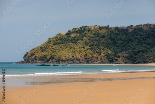 Beautiful beach with golden sand and coastline with boats moored near the shore in the Con Dao archipelago, South China Sea, Vietnam; Con Dao, Ba Rịa - Vung Tau, Vietnam