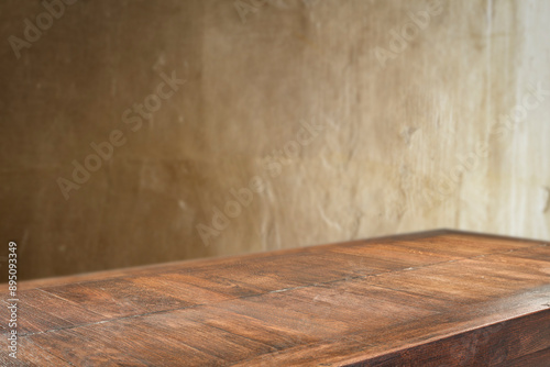 Dark wooden table top with empty copy space and gold structured textured wall backround.