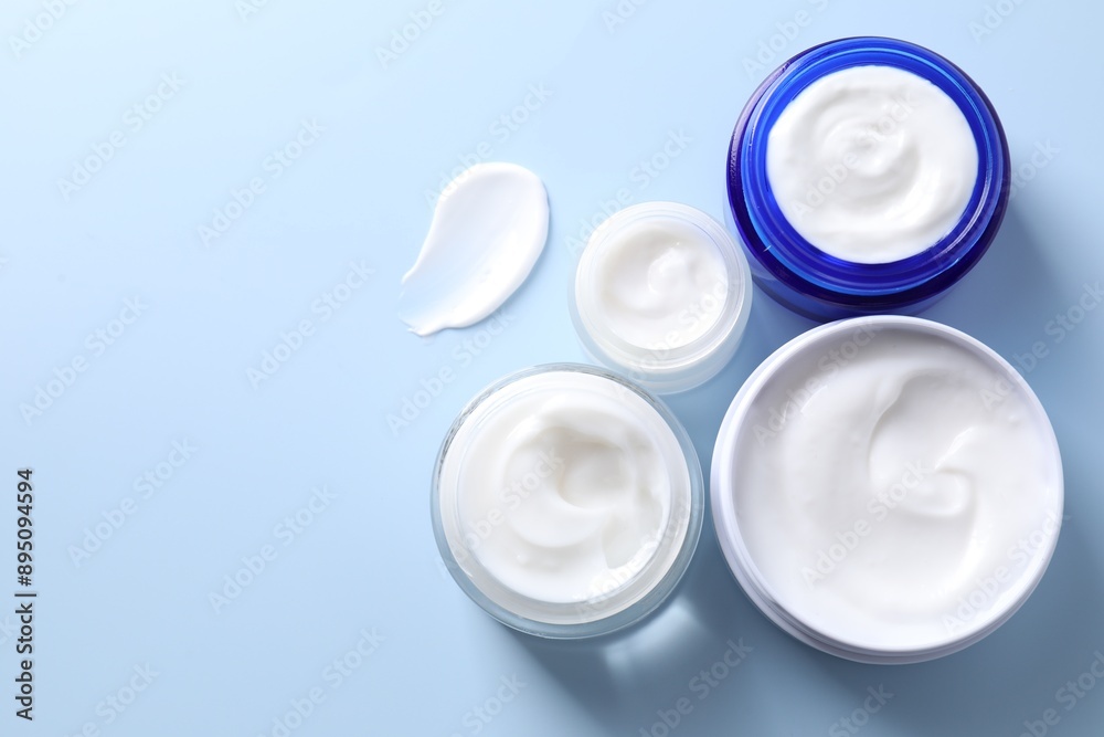 Face cream in jars on light blue background, flat lay. Space for text Face cream in jars on light blue background, flat lay. Space for text