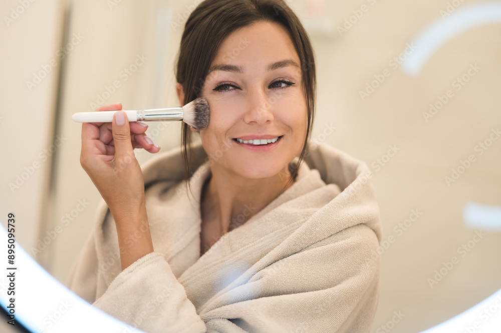 Cute caucasian dark-haired woman at the mirror in the bathroom Cute caucasian dark-haired woman at the mirror in the bathroom
