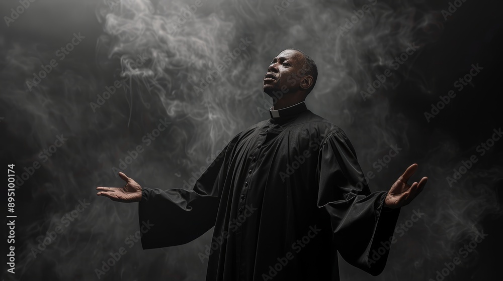 Man in black robe raising hands in smoky atmosphere Man in black robe raising hands in smoky atmosphere