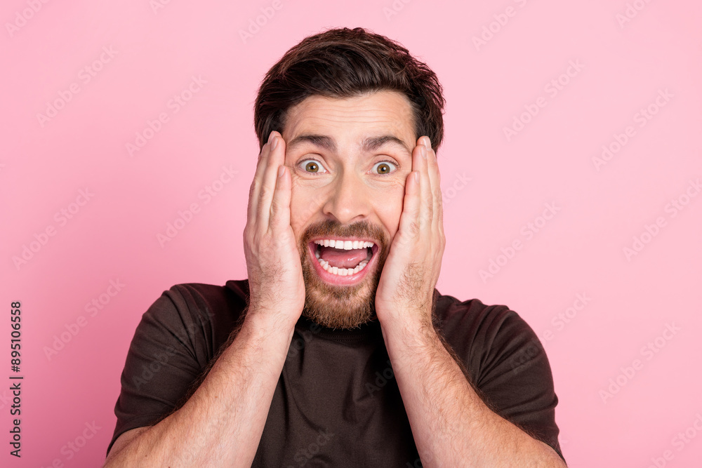 Photo of astonished speechless guy with stubble brunet hair dressed brown t-shirt hold palms on cheeks isolated on pink color background