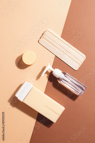 Top view of depilation tools on a beige brown background: cosmetology, hair removal, beauty treatment concept in minimalist aesthetic composition.