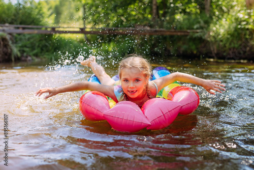 a girl child swims in the water of the river inflatable mattress laughter joy splashes summer heat