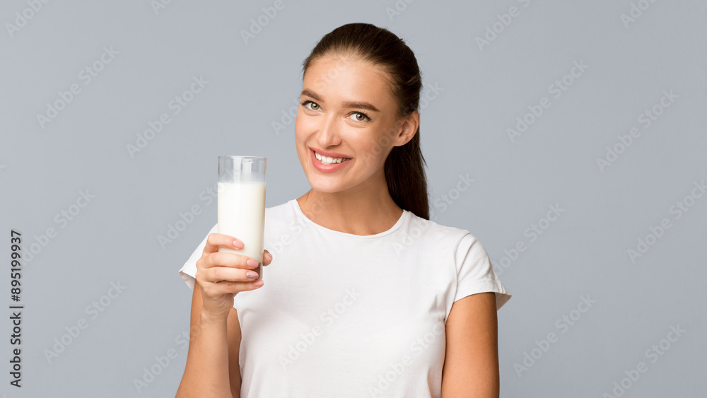 Dairy Products. Millennial Girl Holding Glass Of Milk Smiling To Camera Standing On Gray Background. Studio Shot, Panorama Dairy Products. Millennial Girl Holding Glass Of Milk Smiling To Camera Standing On Gray Background. Studio Shot, Panorama