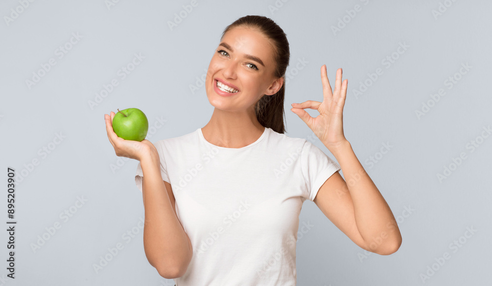 Healthy Eating. Cheerful Woman Holding Apple Fruit And Gesturing Okay Sign Approving Diet Posing On White Studio Background Healthy Eating. Cheerful Woman Holding Apple Fruit And Gesturing Okay Sign Approving Diet Posing On White Studio Background