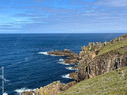 A beautiful cliff rises majestically above the ocean, its rugged rocks contrasting with the deep blue waters below. 
