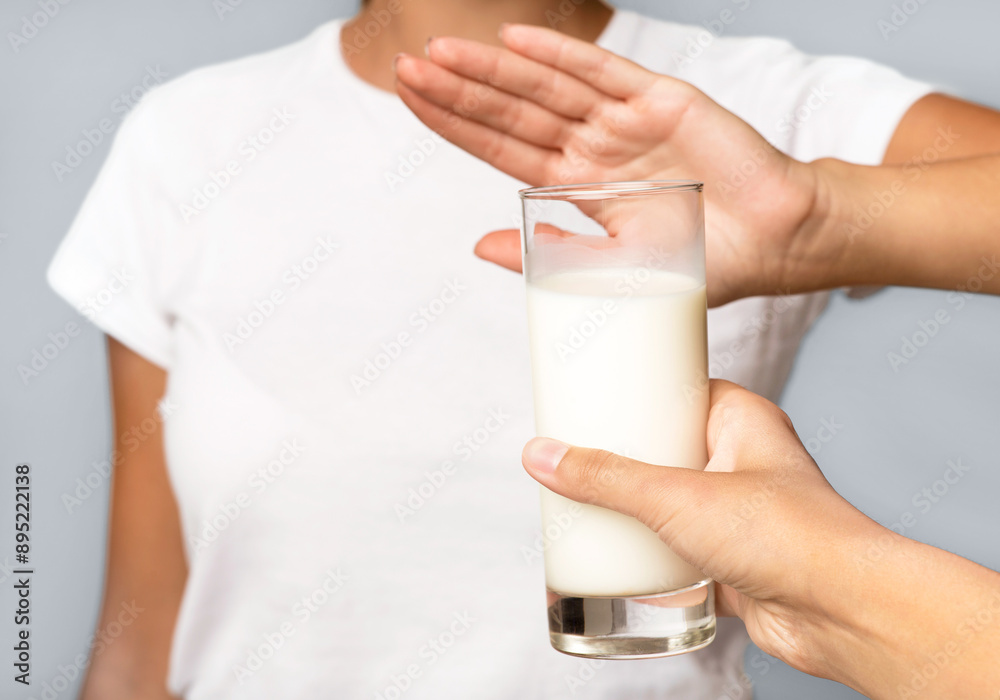 Lactose Intolerance. Unrecognizable Girl Gesturing No To Glass Of Milk Standing Over White Studio Background. Cropped Lactose Intolerance. Unrecognizable Girl Gesturing No To Glass Of Milk Standing Over White Studio Background. Cropped