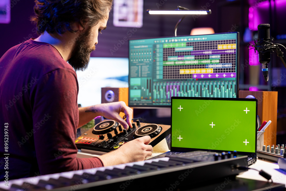 Audio engineer pushing pre amp knobs on mixing console in home studio, using laptop with greenscreen display. Music composer editing soundtracks, stereo instrument on daw software. Audio engineer pushing pre amp knobs on mixing console in home studio, using laptop with greenscreen display. Music composer editing soundtracks, stereo instrument on daw software.