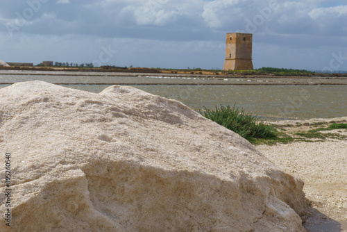 Salt heap at nature reserve Saline di Trapani with salt fields and Torre Nubia on a sunny day, Contrada Nubia, Sicily, Italy