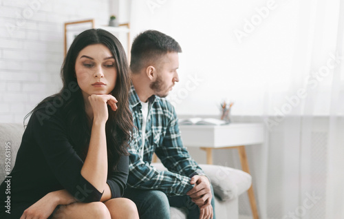 Fényképezés A young woman sits on a sofa with a troubled expression, her chin resting on her hand