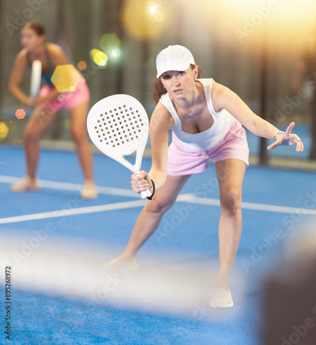 Young and adult women in doubles play tennis on tennis court photo