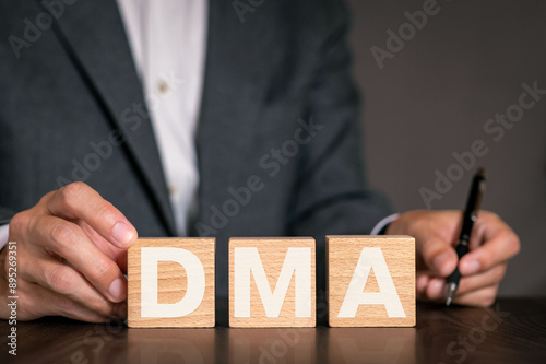 There is wood cube with the word DMA. It is an abbreviation for Digital Markets Act as eye-catching image.