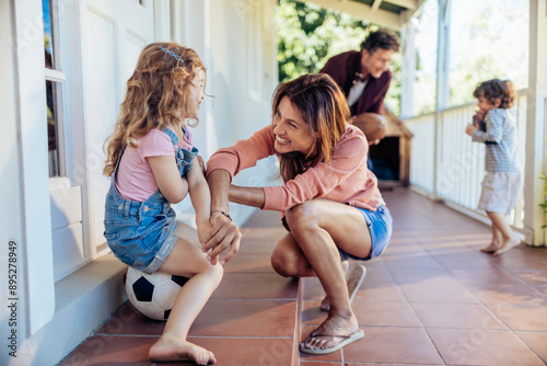 Smiling mother playing with daughter on home porch