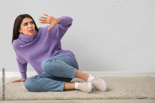 Scared young woman on grey ...