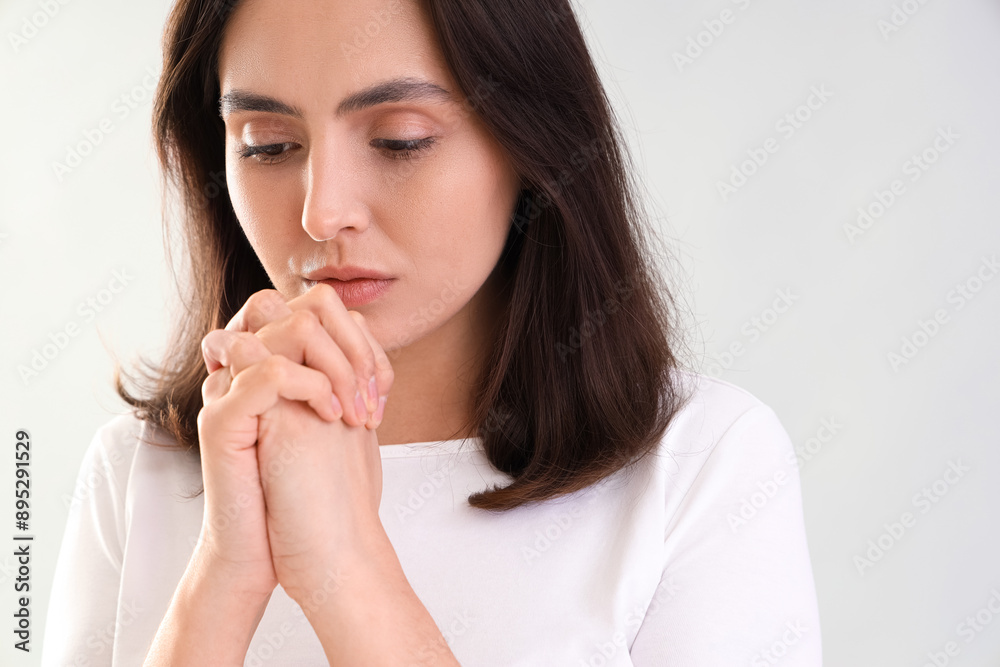 Young woman praying on light background, closeup Young woman praying on light background, closeup