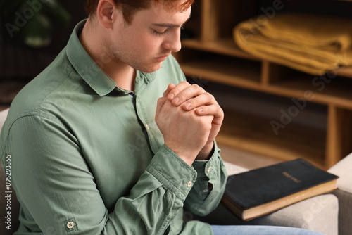 Young man praying on sofa a...