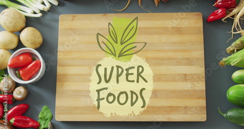 Obraz na plátně Super Foods text image over wooden cutting board surrounded by fresh vegetables