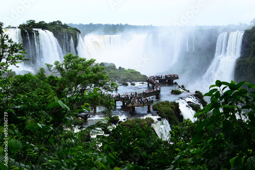 Brazil, Argentina - December 9, 2019: High angle of tourists on deck observatory on Iguazu Falls amid tropical forest
 photo