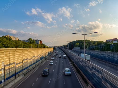 Passenger cars on a multi-line highway in the city at sunset. photo