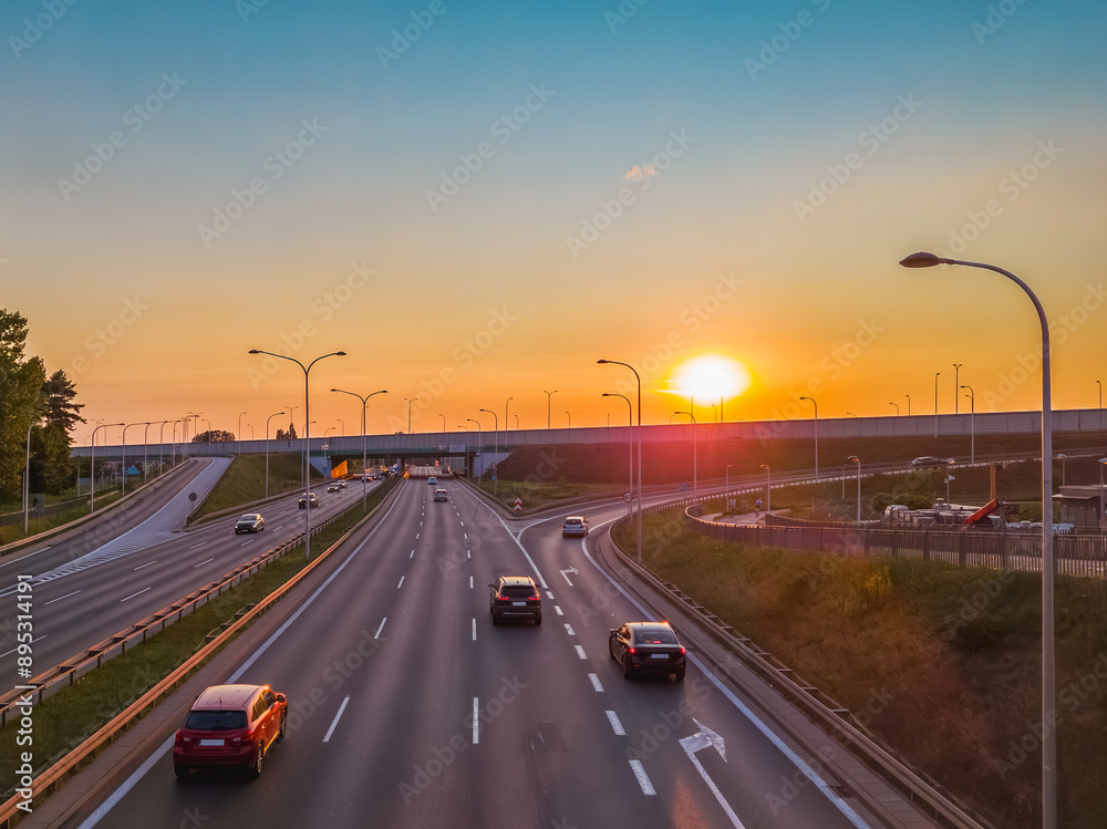 Passenger cars on a multi-line highway in the city at sunset. Passenger cars on a multi-line highway in the city at sunset.