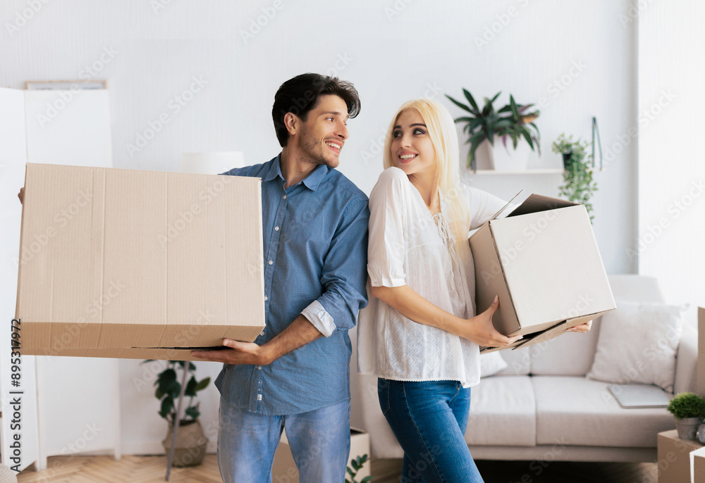 A couple smiling and holding cardboard boxes in a new house. A couple smiling and holding cardboard boxes in a new house.