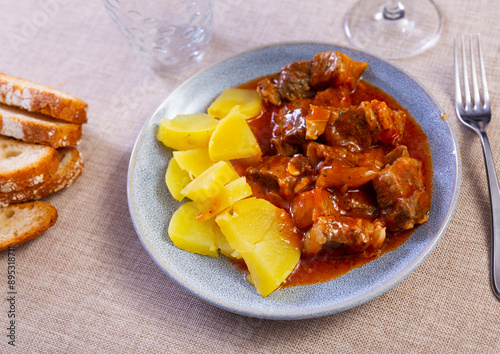 Appetizing braised beef meat in thick spicy tomato gravy served with boiled potato slices .. photo