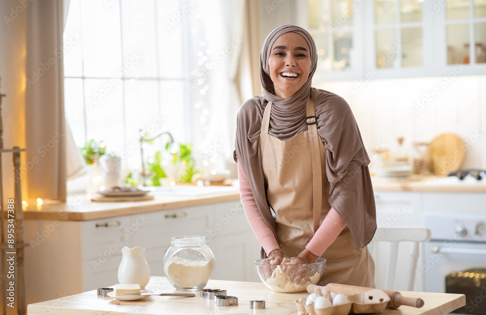 Baking Concept. Portrait Of Joyful Muslim Woman In Hijab Kneading Dough In Kitchen Interior, Cheerful Islamic Female In Hijab And Apron Having Fun While Preparing Homemade Pastry, Laughing At Camera Baking Concept. Portrait Of Joyful Muslim Woman In Hijab Kneading Dough In Kitchen Interior, Cheerful Islamic Female In Hijab And Apron Having Fun While Preparing Homemade Pastry, Laughing At Camera