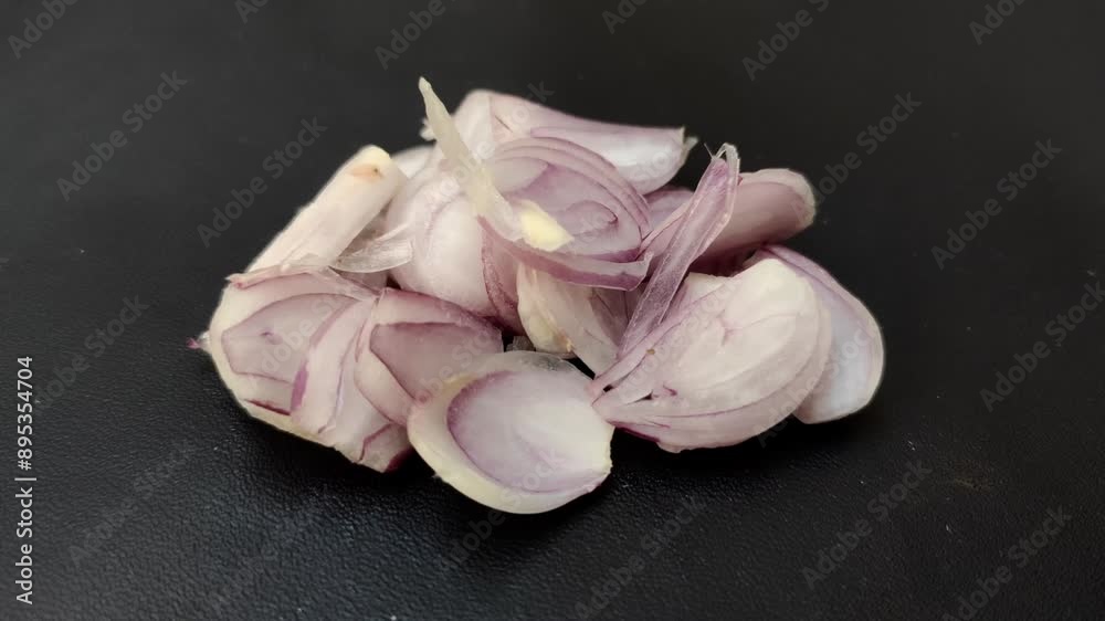 Pieces of fresh red onions or shallots (Allium cepa L. var. Aggregatum) with a black background. That can be eaten raw for cooking spices, pickles, and traditional medicine. Pieces of fresh red onions or shallots (Allium cepa L. var. Aggregatum) with a black background. That can be eaten raw for cooking spices, pickles, and traditional medicine.