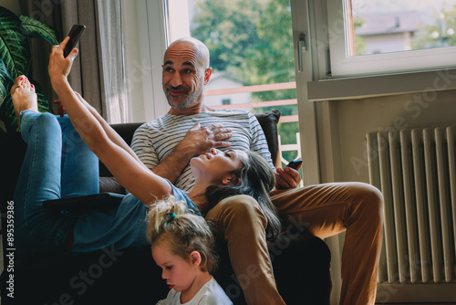 Happy family taking selfie while relaxing on sofa at home